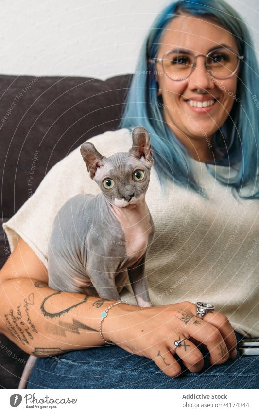 Happy female with hairless cat woman sofa rest smile home happy pet owner cute casual couch domestic joy sphynx animal lifestyle cheerful contemporary adorable