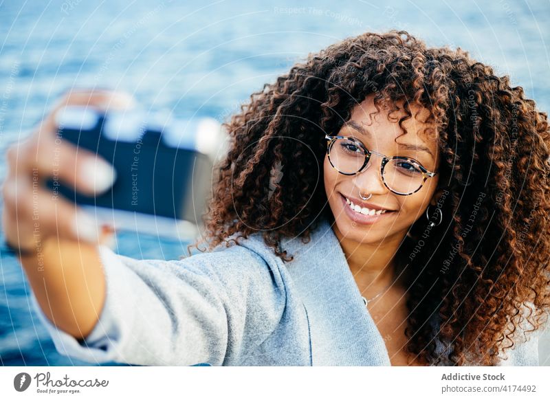 Happy African American female taking selfie near sea woman smile weekend photo camera water shore young ethnic black african american two fingers sign relax