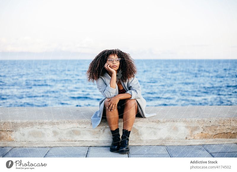 Cheerful black female sitting on embankment woman sea smile style weekend happy outfit rest young quay cheerful ethnic african american water delight relax