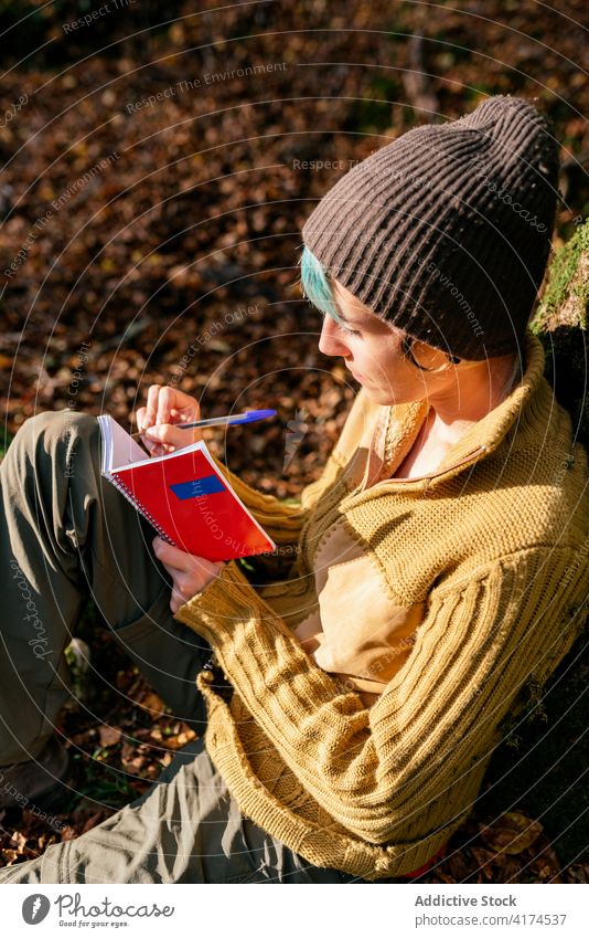 Traveling woman taking notes in notebook in forest traveler take note woods write diary vacation adventure female tree trunk tourism lean sit peaceful nature