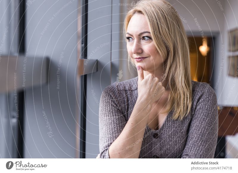 Woman looking away in modern building woman female interior window outbreak style stand lady charming smile content daytime delight indoors blur horizontal