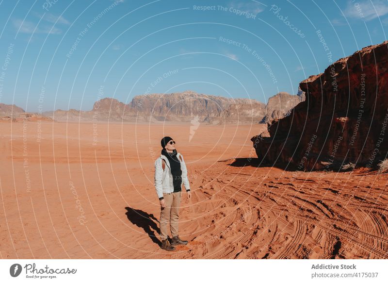 Traveler standing in desert with mountains during vacation traveler sandstone valley explore tourist arid dry nature wanderlust wadi rum jordan outerwear