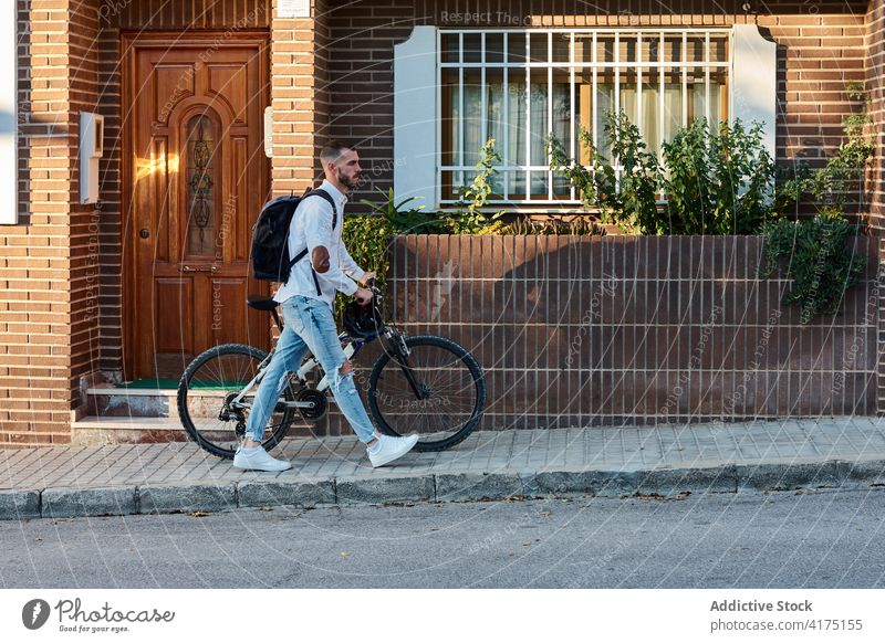 Hipster man with bicycle walking on street hipster urban bike trendy backpack modern male adult lifestyle building vehicle transport pedestrian activity