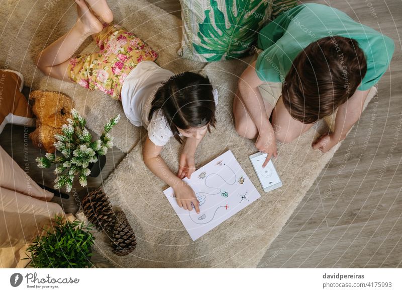 Unrecognizable children playing treasure hunt at home on the carpet top view unrecognizable treasure hunting game mobile compass map looking stay at home