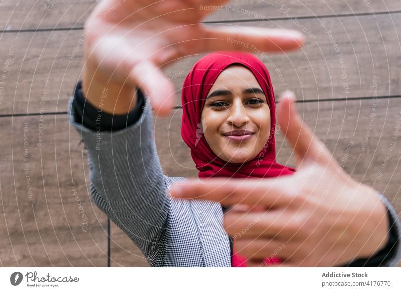 Smiling ethnic woman in headscarf showing framing gesture frame smile capture sign hijab muslim photo female arab optimist happy cheerful crop composition