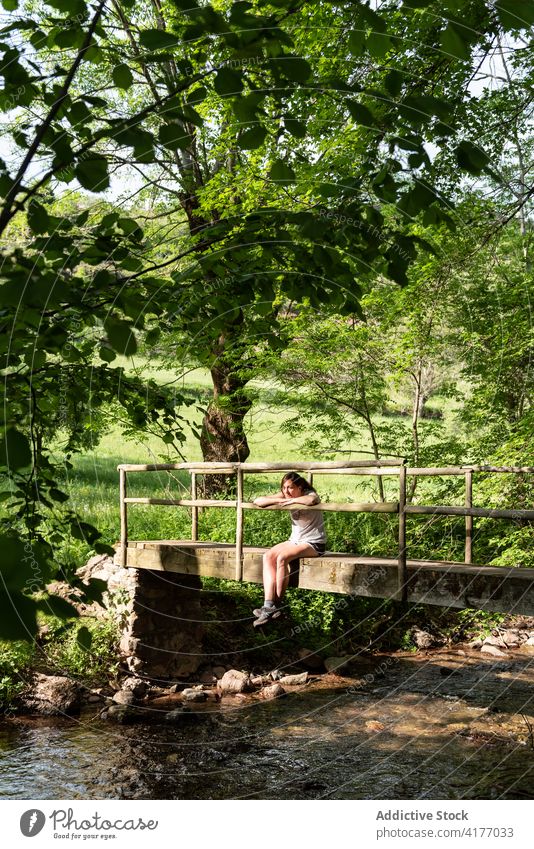 Woman relaxing on bridge in forest woman woods summer river enjoy carefree nature female peaceful tree sit freedom water creek brook old tranquil calm