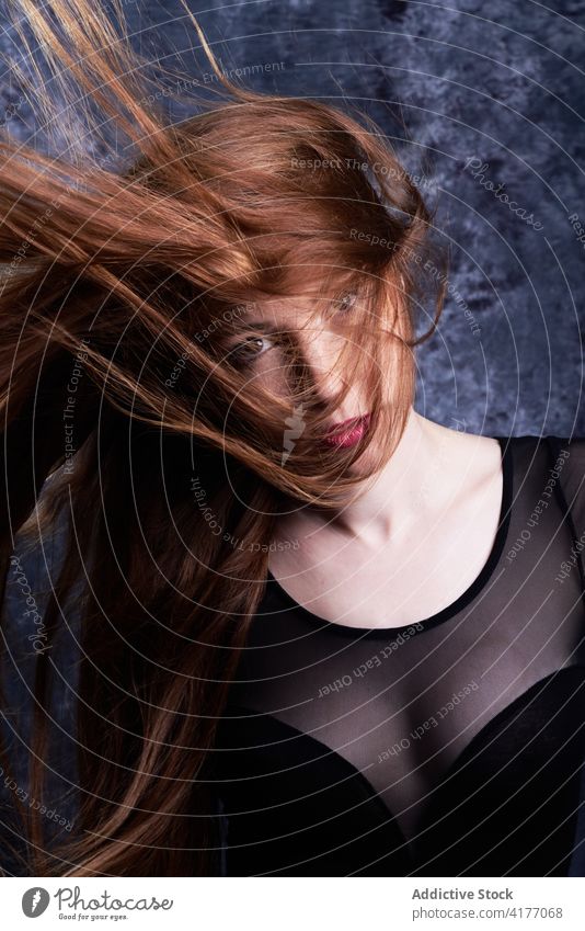 Tranquil woman with flying hair in studio redhead appearance style calm model fashion long hair female charming red hair stand outfit personality confident