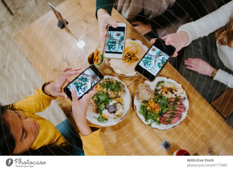 Company of women taking photos of food in cafe food photography blogger take photo together smartphone social media dish multiethnic multiracial diverse table