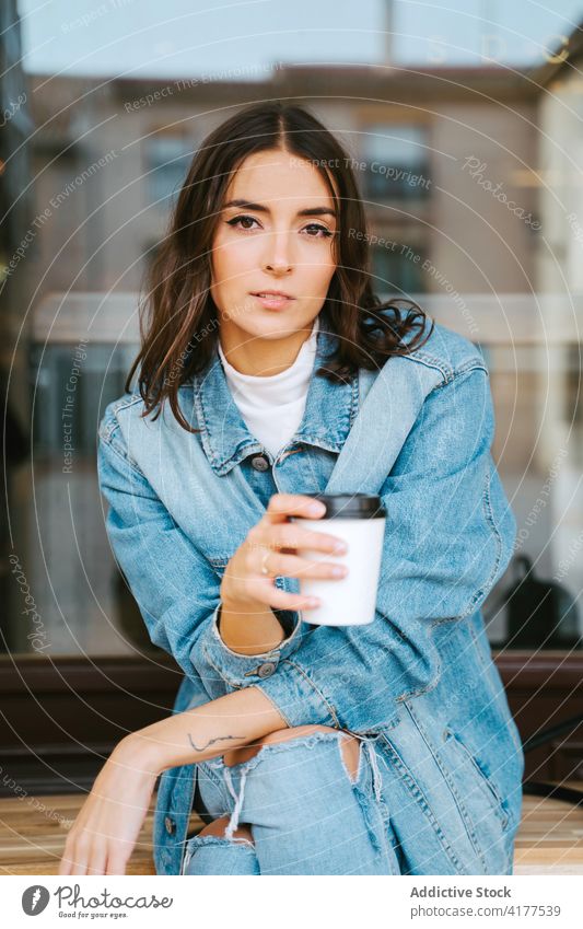 Young woman with takeaway coffee resting on street drink cup denim modern relax urban calm young female disposable to go beverage lifestyle free time chill