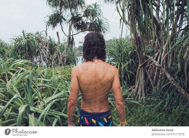 Anonymous shirtless ethnic man standing in jungle sea tropical exotic nature traveler male tourism bay sri lanka hiriketiya journey green coast shore lifestyle