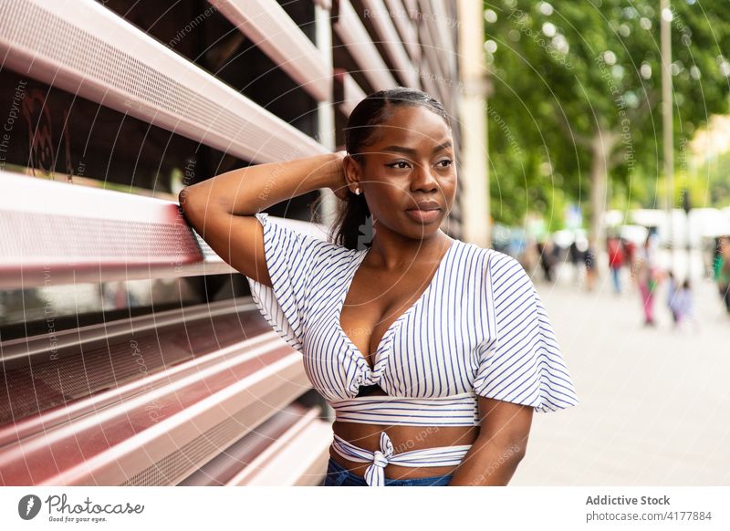 Black woman in stylish wear looking away on street style trendy outfit modern urban stripe young summer female african american black ethnic calm relax