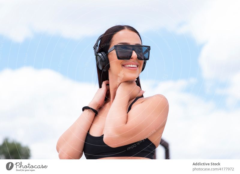 Trendy fit woman in headphones and sunglasses trendy style positive cheerful sporty happy young female wireless listen music fashion lifestyle smile optimist