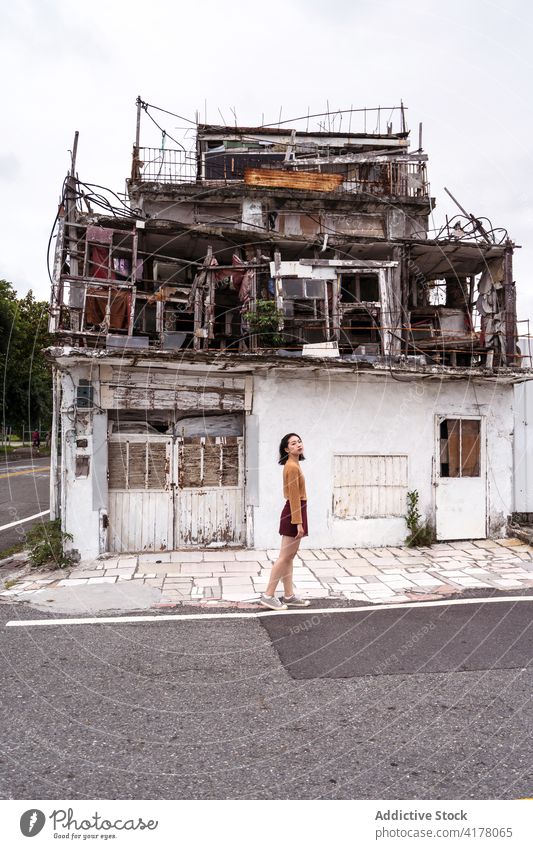 Woman standing near weathered building in city shabby street woman aged grunge abandoned exterior ancient old female east coast structure town daytime facade