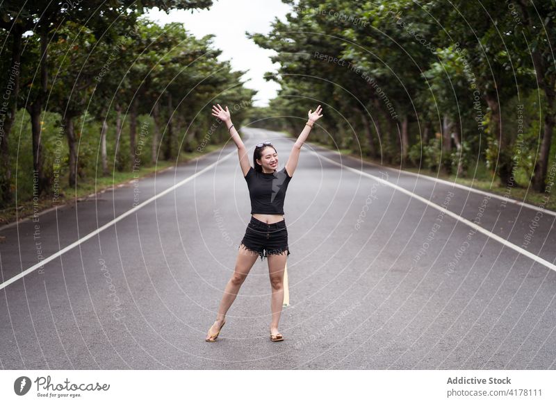 Young woman standing on asphalt road in forest park traveler positive way path nature explore young asian female ethnic kenting taiwan active tree happy smile