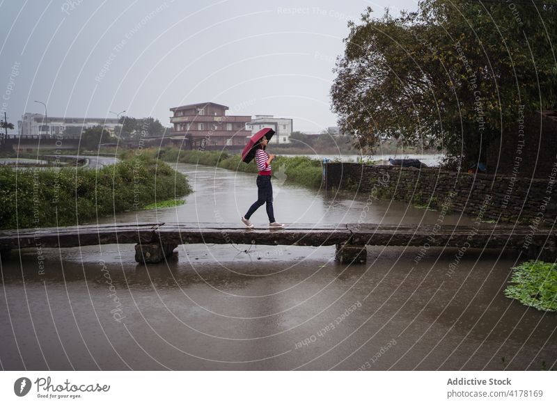 Woman walking on rainy day under umbrella woman solitude city enjoy bridge cross gloomy melancholy female yilan county taiwan wooden footbridge young weather