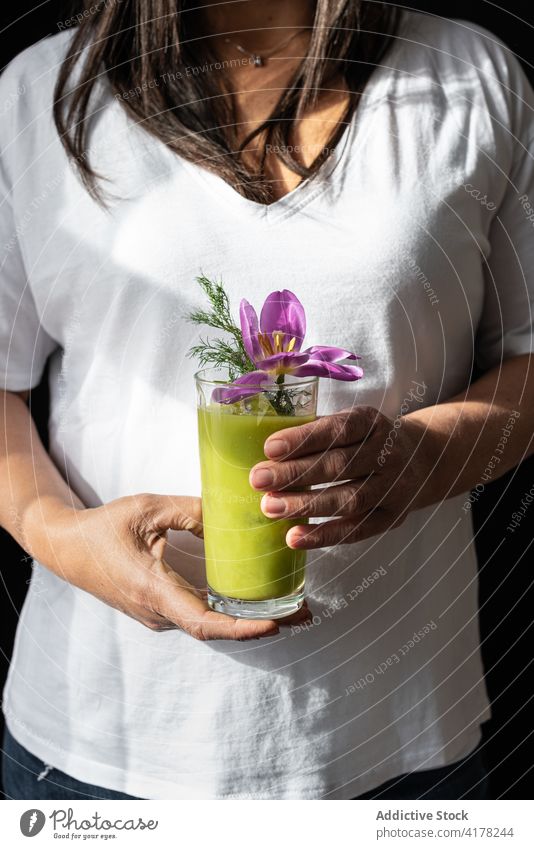 Crop woman with glass of green detox drink matcha flower herb healthy nutrition female fresh delicious natural organic tasty smoothie energy vegan diet wellness