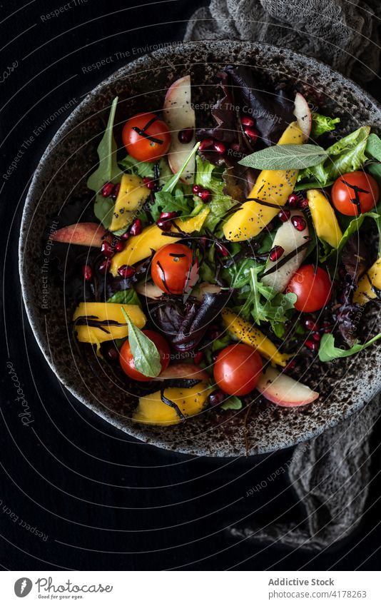 Bowl of appetizing salad made of fresh fruits and vegetables mix ripe lunch delectable bowl serve peach cherry tomato mango basil rucola green greenery herb