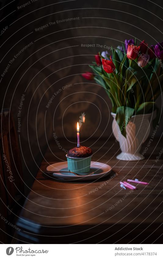 Chocolate cupcake with candle on table with flowers festive birthday food pastry chocolate sweet dessert celebrate holiday event delicious bouquet romantic