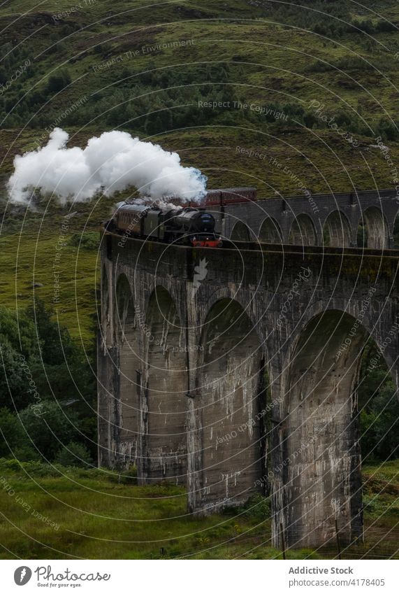 Steam train riding along railway viaduct glenfinnan viaduct steam landmark famous railroad mountain scotland united kingdom uk cloudy destination sky scenic
