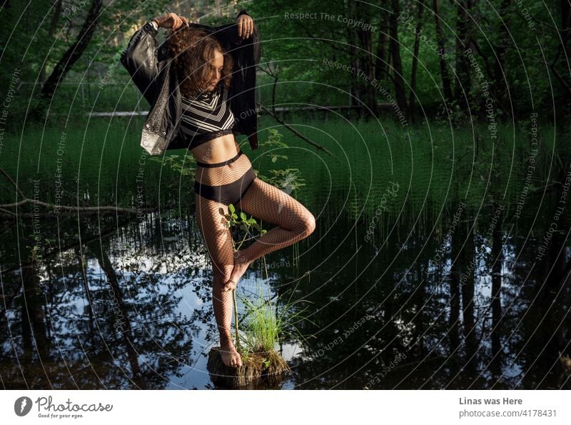 A gorgeous woman is practicing her dance moves in the middle of a muddy swamp. Wild girl in wild nature. Summer adventures are just beginning. pretty woman lake