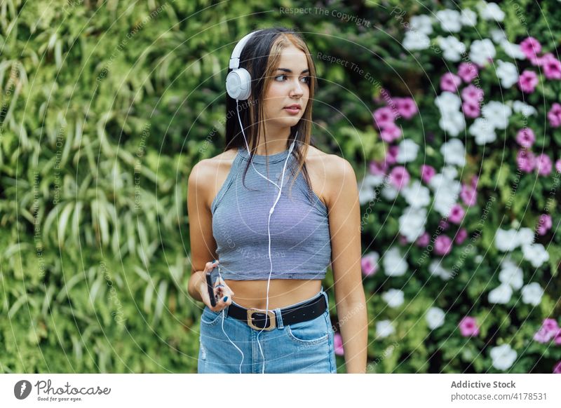 Woman with smartphone and headphones chilling in park woman listen having fun cheerful summer mobile music young female gadget device lifestyle enjoy using