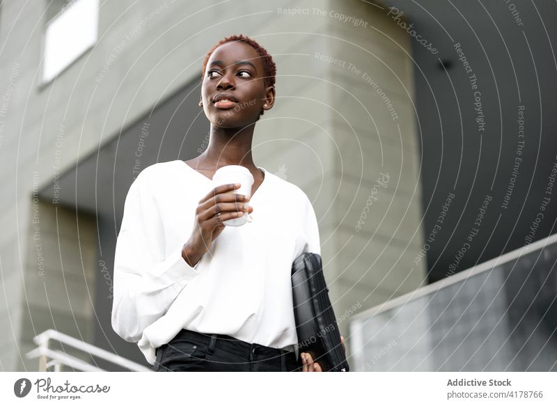 Cheerful ethnic businesswoman with takeaway coffee on street positive elegant modern urban drink cheerful style young black african american short hair to go