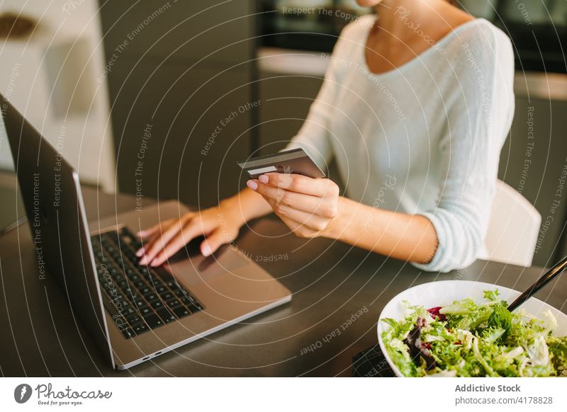 Unrecognizable woman doing online purchase on laptop at home credit card using payment order internet young female gadget device e commerce connection lifestyle