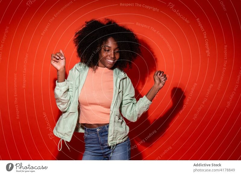 Cheerful black woman dancing in red studio style dance casual energy cheerful colorful posture vivid bright ethnic african american cuban hairstyle afro
