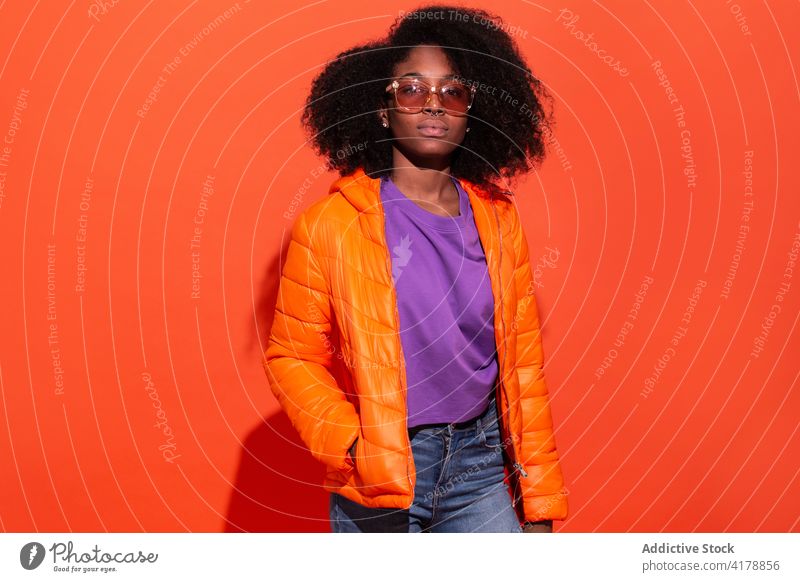 Stylish black woman with Afro hairstyle vivid casual trendy colorful sunglasses contemporary bright chic jacket cool fashion purple orange accessory millennial