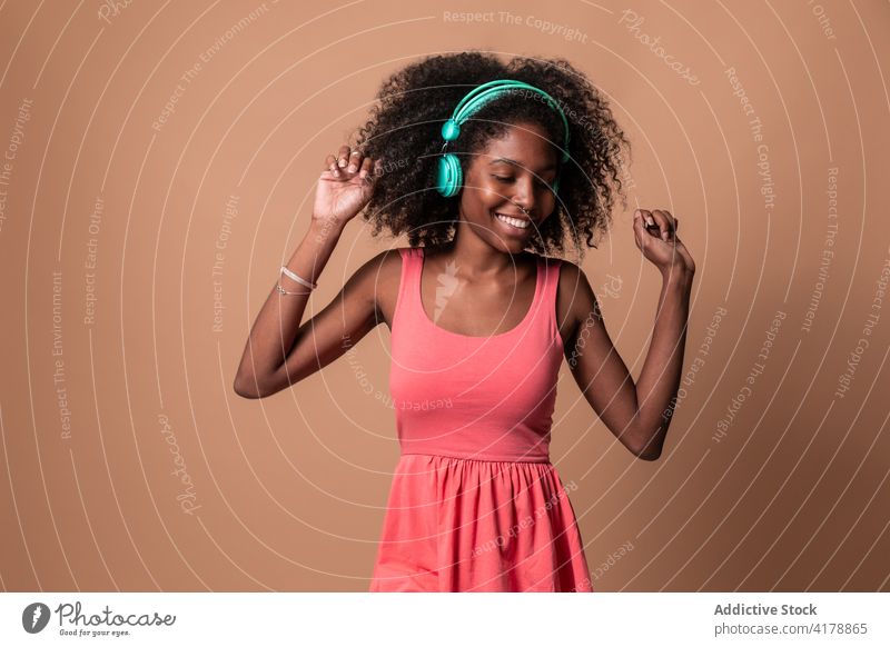 Ethnic woman with headphones dancing in studio dance fun music happy style colorful hairstyle afro ethnic cuban african american black smile trendy dress