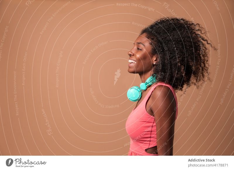 Ethnic woman with headphones standing in studio fun music happy style colorful hairstyle afro ethnic cuban african american black smile trendy dress carefree