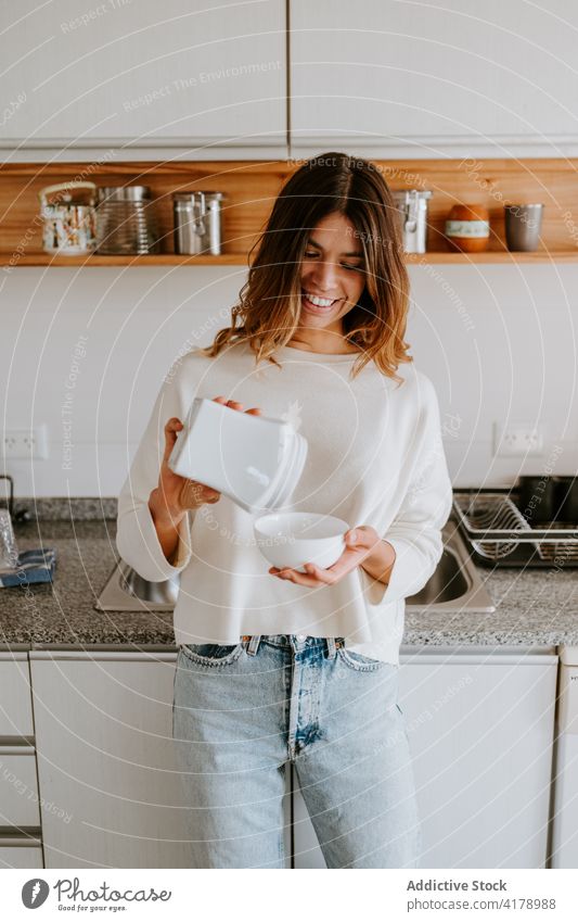 Positive woman making breakfast in morning healthy food diet pour kitchen bowl cheerful female add fresh tasty healthy lifestyle content home delicious smile