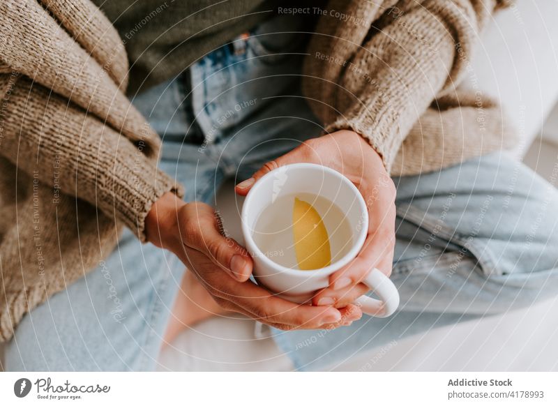 Crop woman with cup of water with lemon detox diet morning healthy refreshment drink natural female slice home rest sit cozy organic nutrition slim ingredient