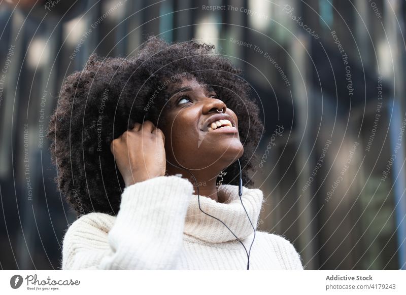 Happy black woman in earphones listening to music on smartphone optimist cheerful chill enjoy young having fun positive african american afro ethnic curly hair