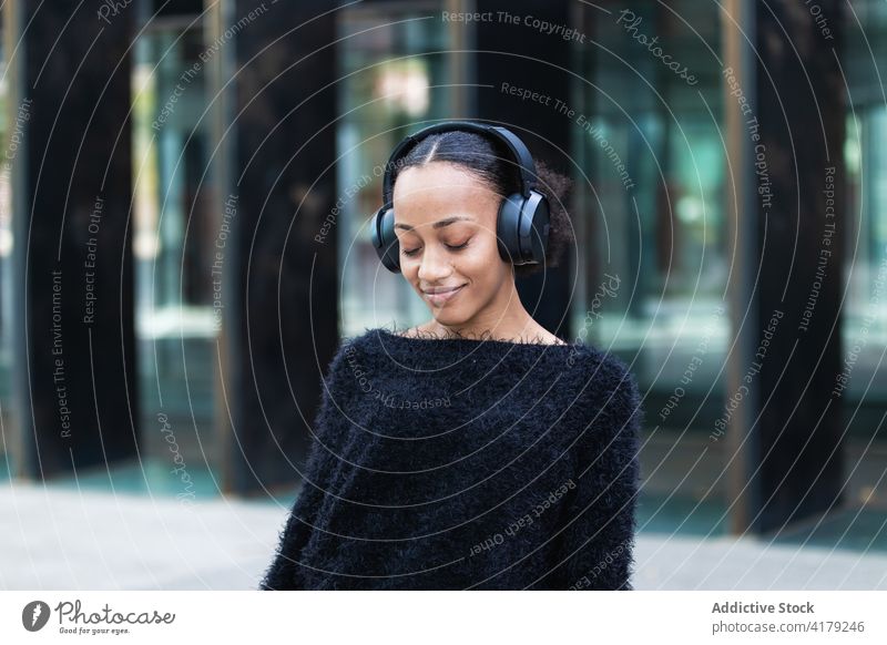 Black woman listening to music on the street headphones chill enjoy young wireless positive african american black ethnic student adolescent optimist female