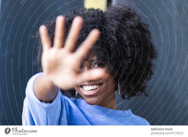 Smiling black woman covering face from camera hide cover face no cheerful smile reject outstretch positive afro young african american ethnic female curly hair