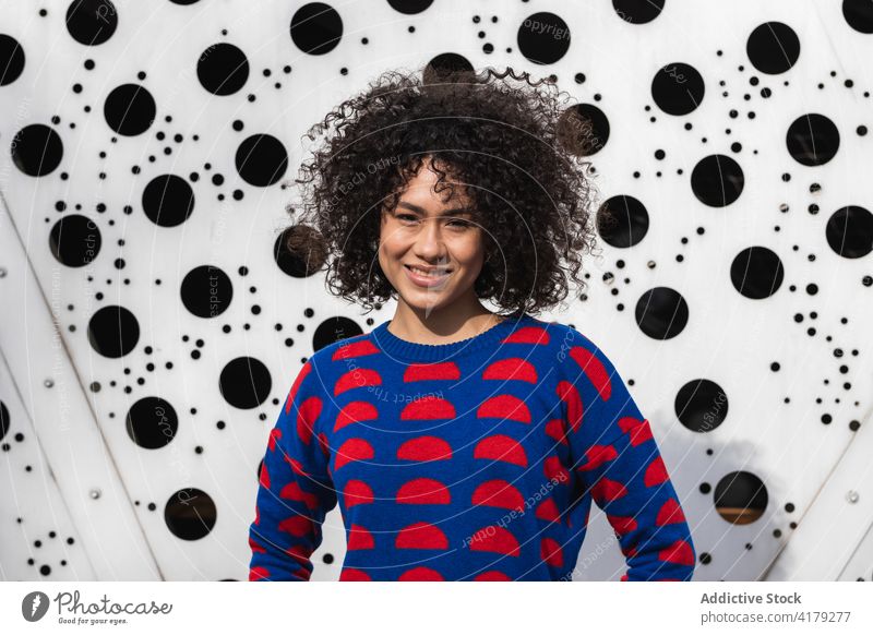 Cheerful black woman in stylish outfit in city afro hairstyle appearance cheerful urban vivid creative female ethnic african american sweater area smile
