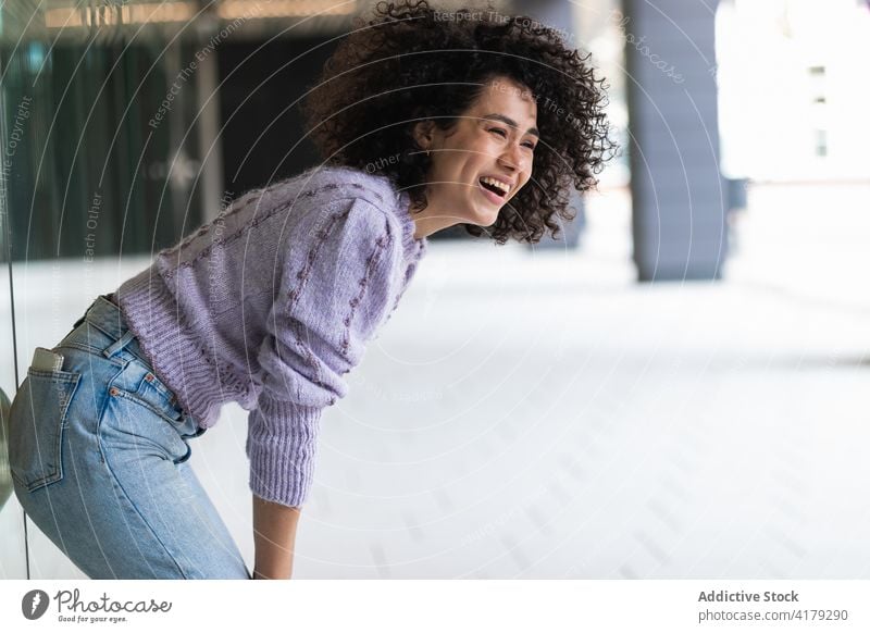 Delighted ethnic woman with flipping hair in city flying hair coquette cheerful playful having fun curly hair female black african american afro hairstyle