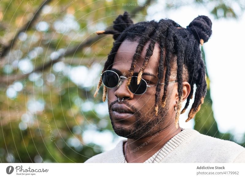 Modern guy with dreadlocks and in accessories man trendy style sunglasses cool modern personality appearance street style culture casual lifestyle handsome