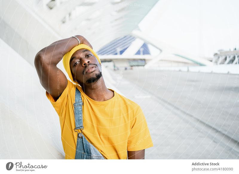 Black man standing in the street looking at camera trendy male ethnic black african american yellow outfit style modern bright appearance garment urban young
