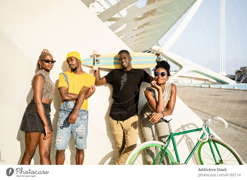 Company of cheerful friends with bike and longboard in city company hipster unity cool style bicycle generation together ethnic black african american people