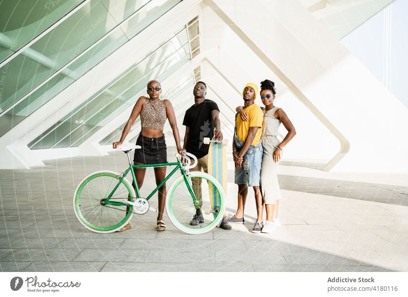 Company of cheerful friends with bike and longboard in city company hipster unity cool style bicycle generation together ethnic black african american people