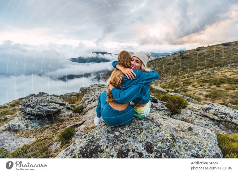 Cheerful women hugging in mountains traveler enjoy vacation friend highland cheerful friendship together adventure rock summer female nature carefree relax sit