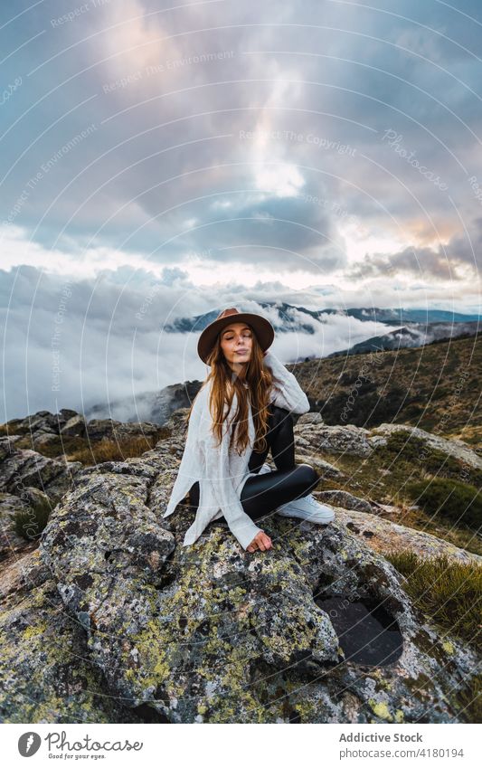 Woman in hat enjoying view of mountains woman observe viewpoint travel tourist highland admire explore female stone scenic sit nature traveler picturesque