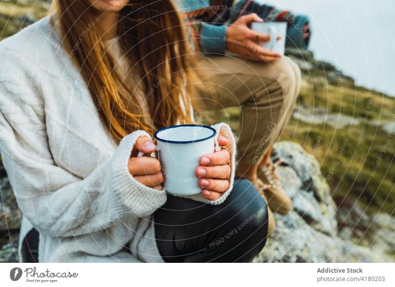 Anonymous women with hot beverage in cups in mountains traveler hot drink highland relax carefree female landscape holiday trip adventure nature tourism friend