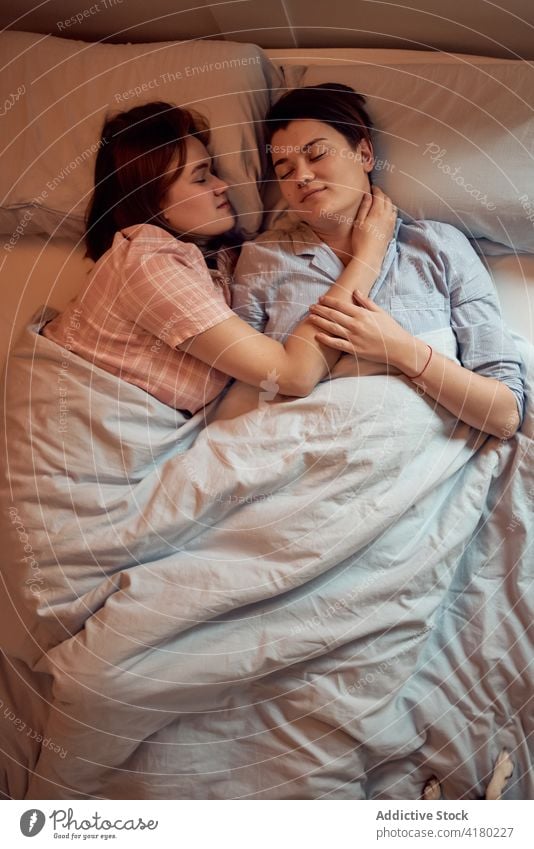 Couple of women lying sleeping on bed couch lesbian relax morning home love relationship together bedroom girlfriend eyes closed romantic soft couple rest