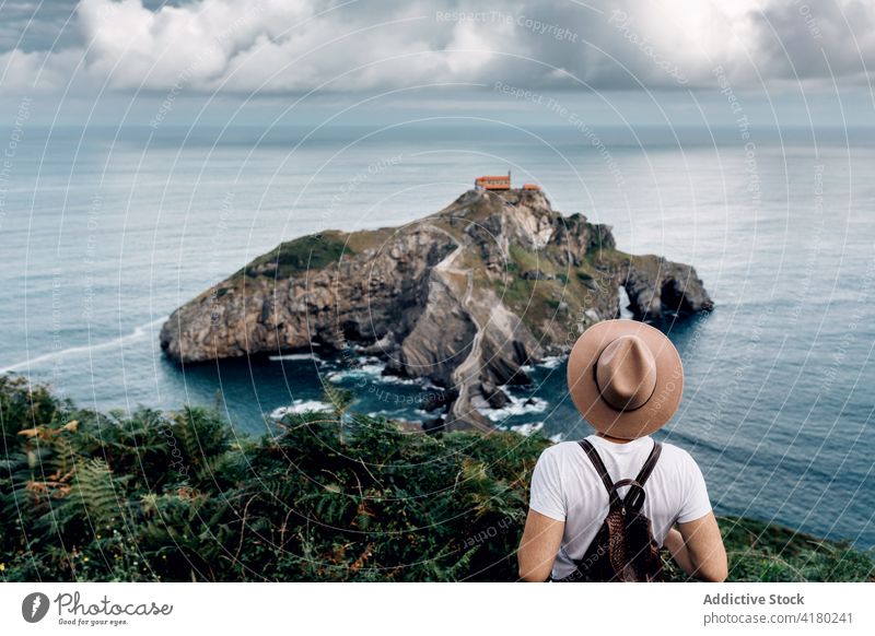 Traveling man standing admiring view of island travel observe sea vacation tourist summer male gaztelugatxe spain holiday water ocean trip scenery tourism relax