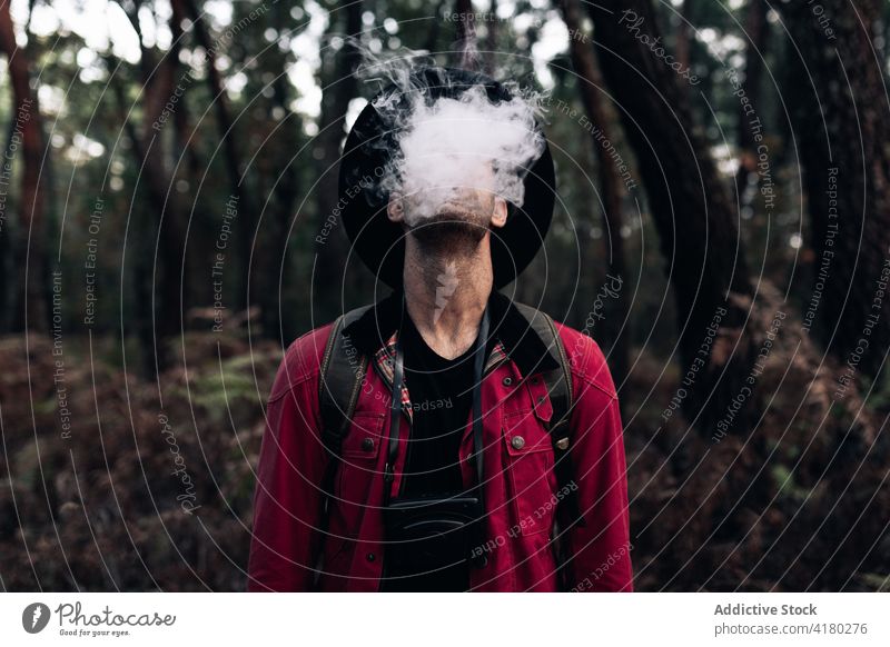 Anonymous man smoking in woods smoke travel exhale nature dark vapor environment tourist nicotine woodland peaceful rest idyllic solitude dream cloud cover face