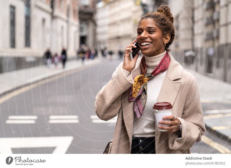 Focused young African American female strolling in city and talking on smartphone woman walk phone call square conversation busy pedestrian style speak