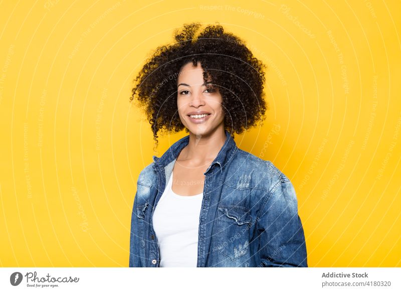 Cheerful ethnic woman in denim shirt looking at camera cheerful smile casual positive trendy happy optimist curly hair young african american black afro style